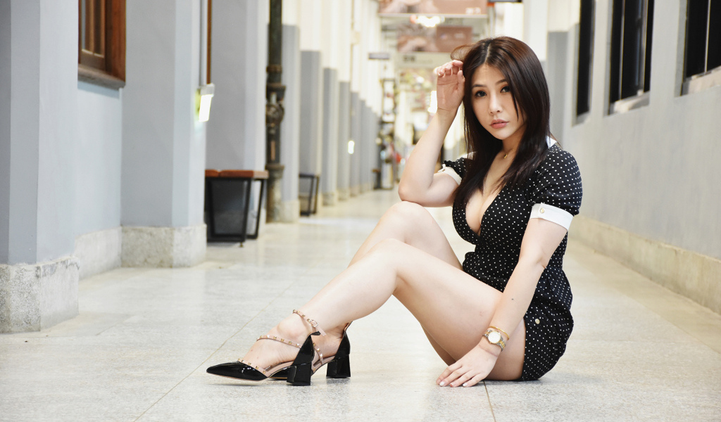 Азиатка в черном платье в горошек сидит на дороге