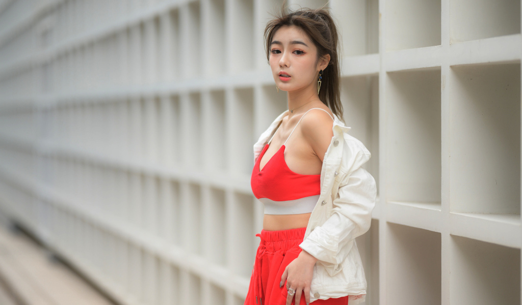 Азиатка в красном спортивном костюме стоит у стены