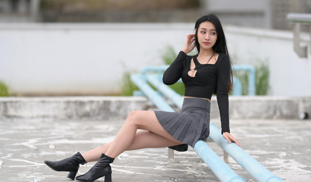 Азиатка в короткой юбке сидит на трубе