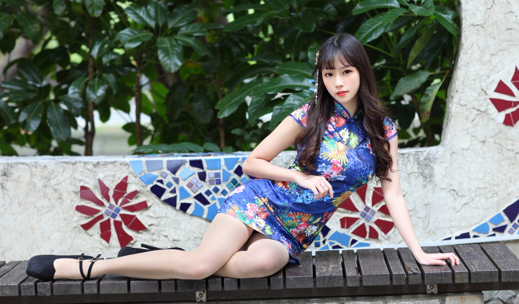 Красивая девушка азиатка в платье лежит на лавке