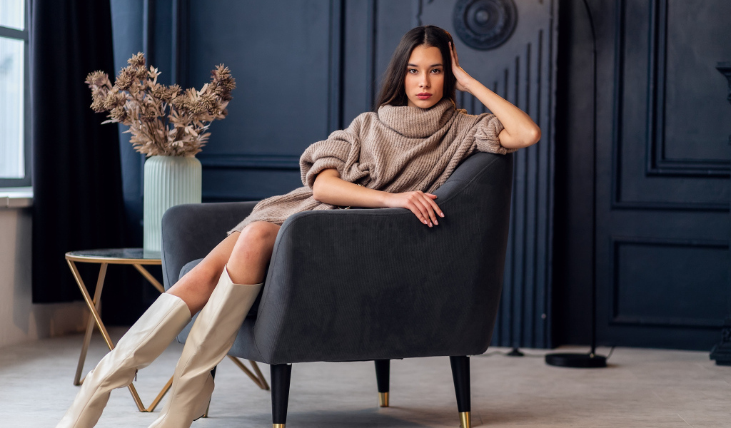 Красивая брюнетка в сапогах сидит в кресле