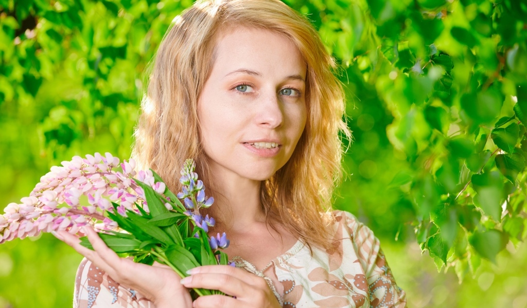 Красивая девушка с цветами люпина в руке
