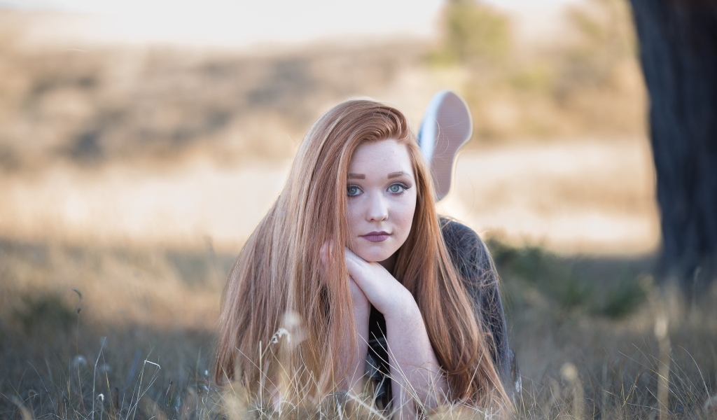 Красивая рыжеволосая девушка лежит на траве