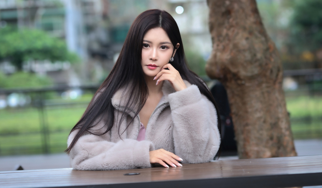 Кареглазая азиатка сидит в парке за столом