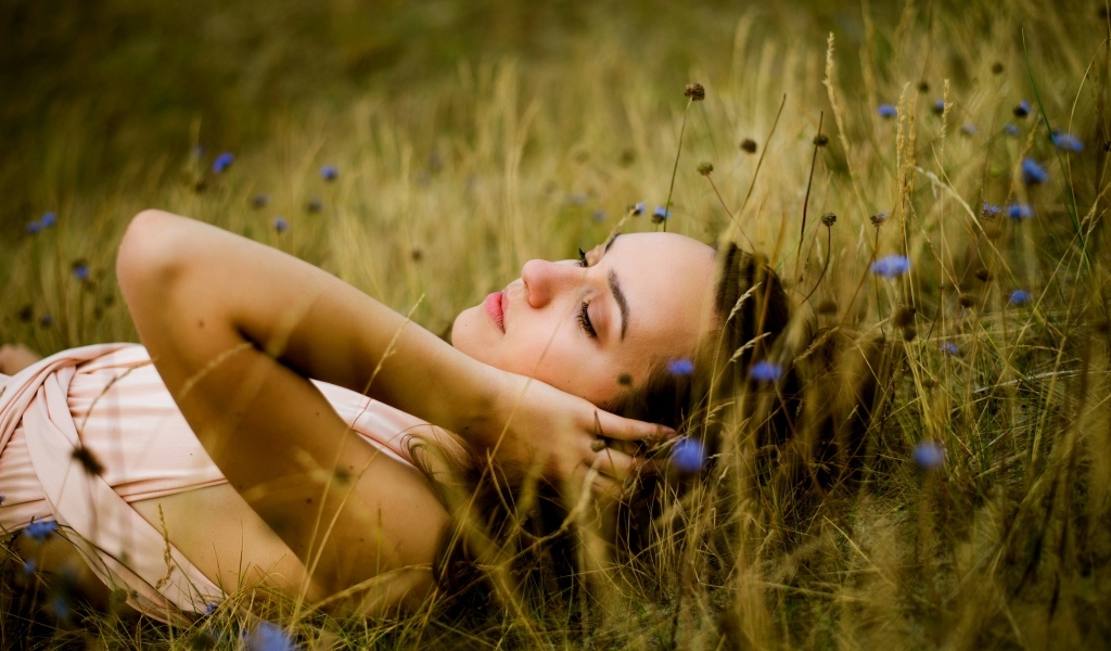 Милая девушка лежит на траве на поле