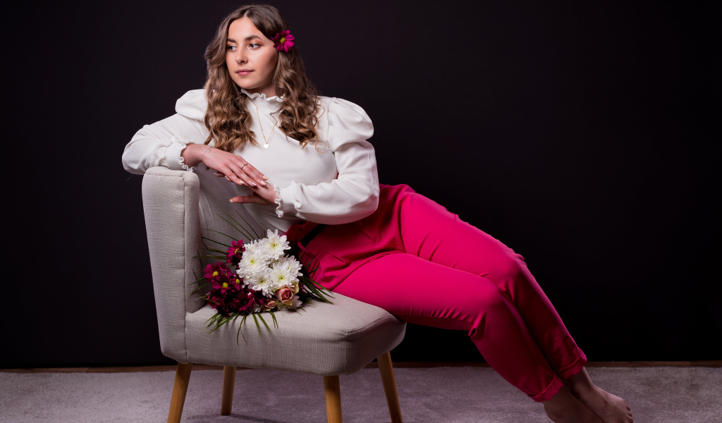 Милая девушка сидит на сером кресле с цветами