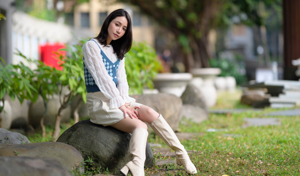 Милая девушка сидит на камне в парке