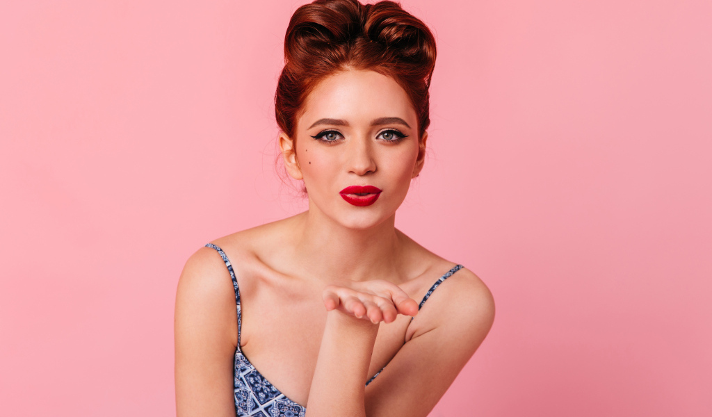 Милая рыжеволосая девушка на розовом фоне