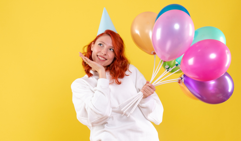 Милая рыжеволосая девушка с шариками на желтом фоне