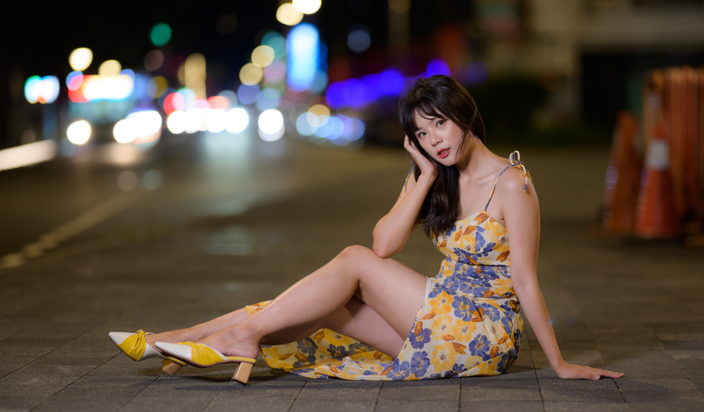 Милая нежная азиатка в платье сидит на дороге