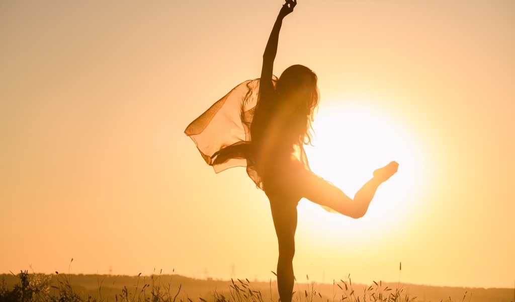 Девушка танцует в лучах солнца на закате