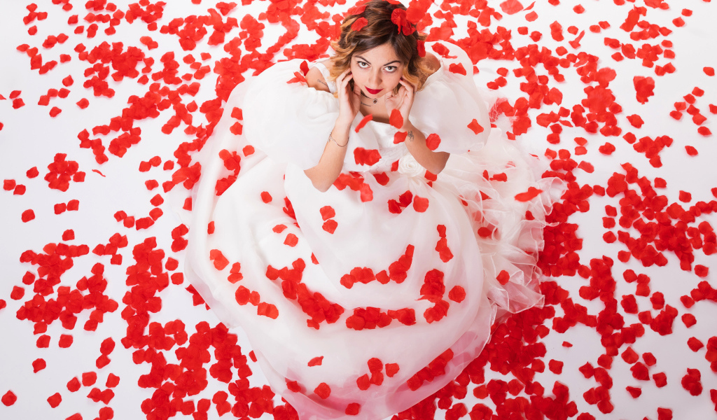 Девушка в белом платье сидит на лепестках розы