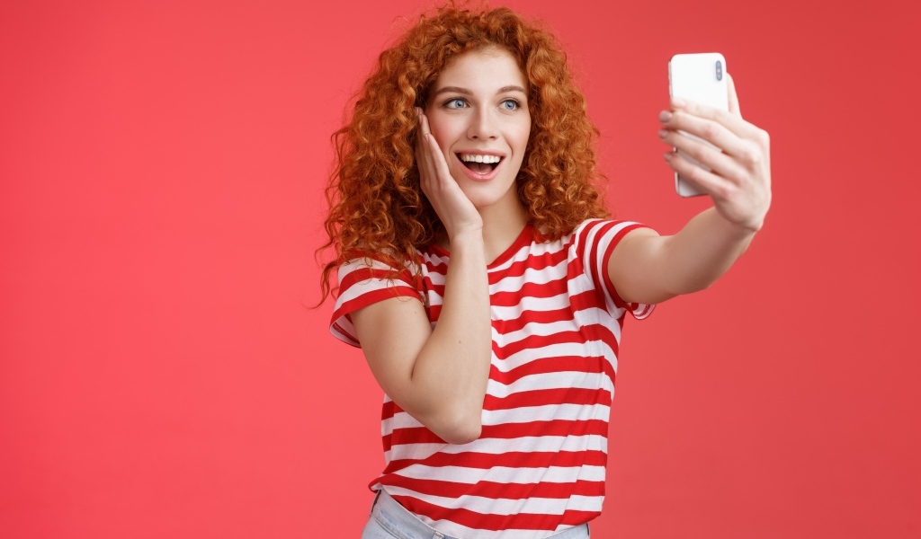 Девушка делает селфи на красном фоне