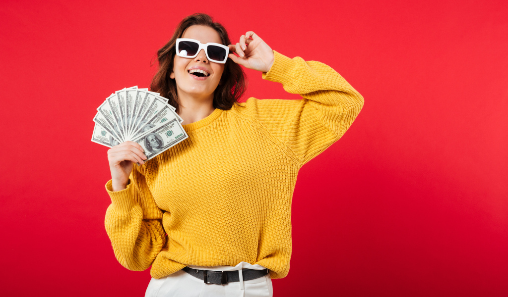 Девушка с веером из долларов на красном фоне