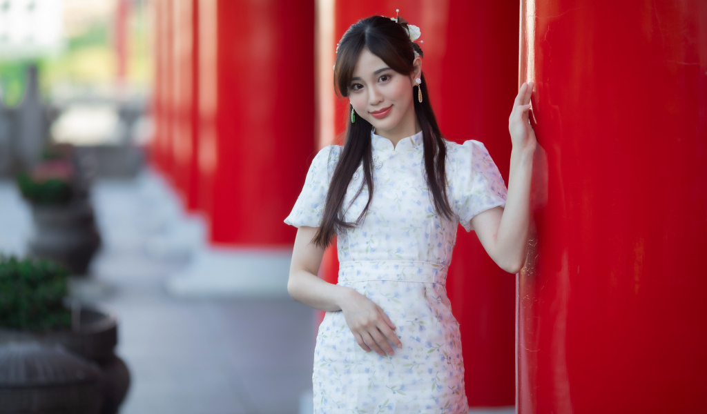 Длинноволосая азиатка позирует у красной колонны