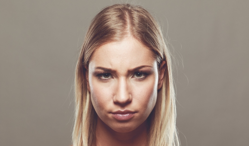 Серьезная девушка с короткой стрижкой на сером фоне