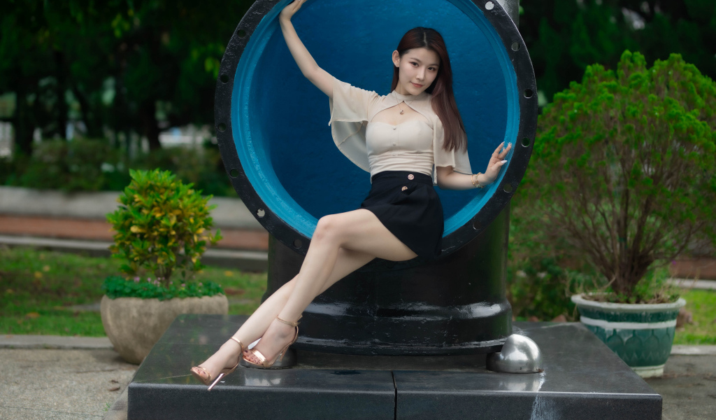 Стройная длинноногая азиатка сидит в трубе