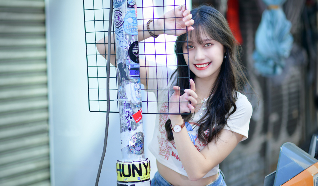 Улыбающаяся азиатка держится за сетку