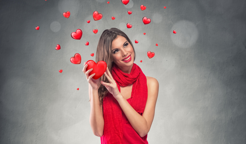 Улыбающаяся девушка в красном платье с сердечками на сером фоне