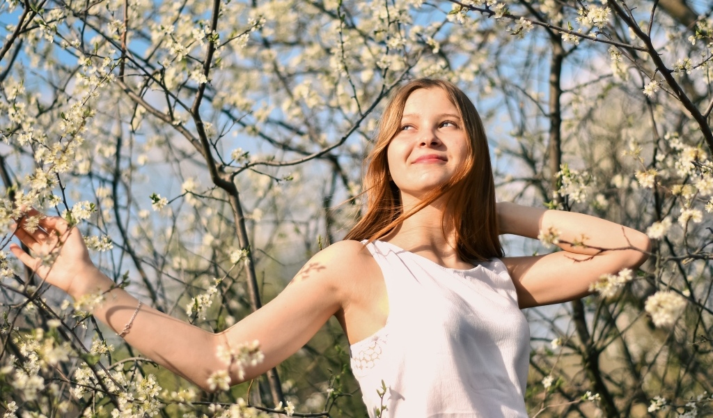 Молодая девушка у цветущего дерева весной