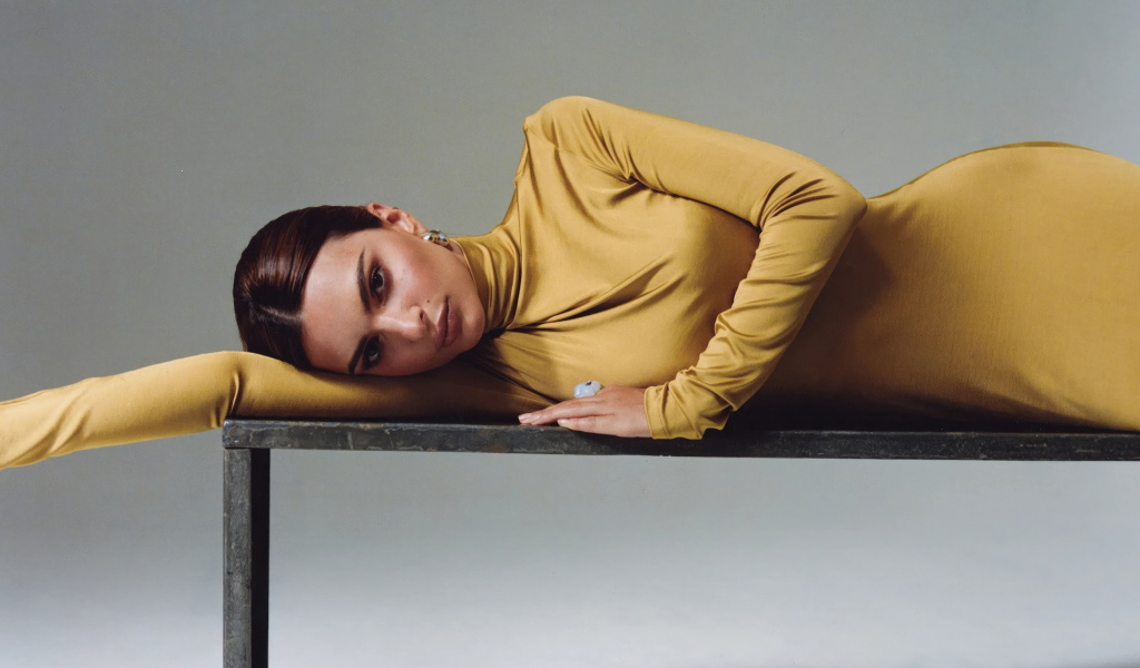 Красивая модель Эмили Ратаковски в желтом платье лежит на столе