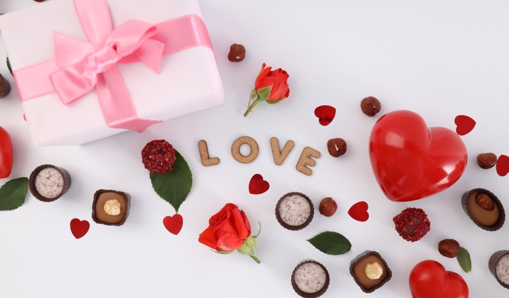 Подарок и сердечки с конфетами на столе на День Святого Валентина