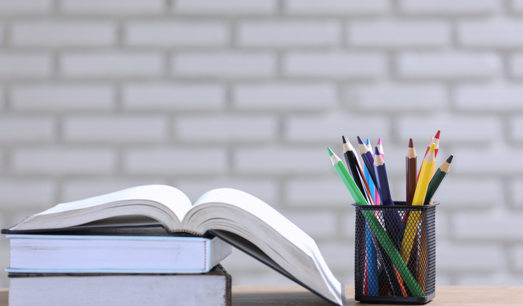 Разноцветные карандаши на столе с книгами 