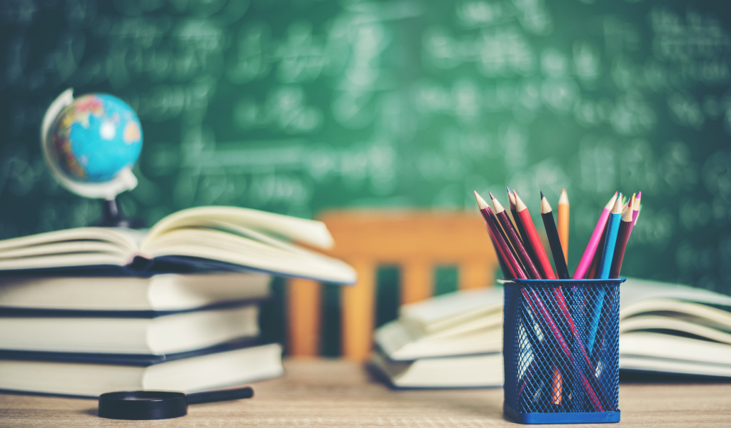 Карандаши на столе с книгами в школьном классе