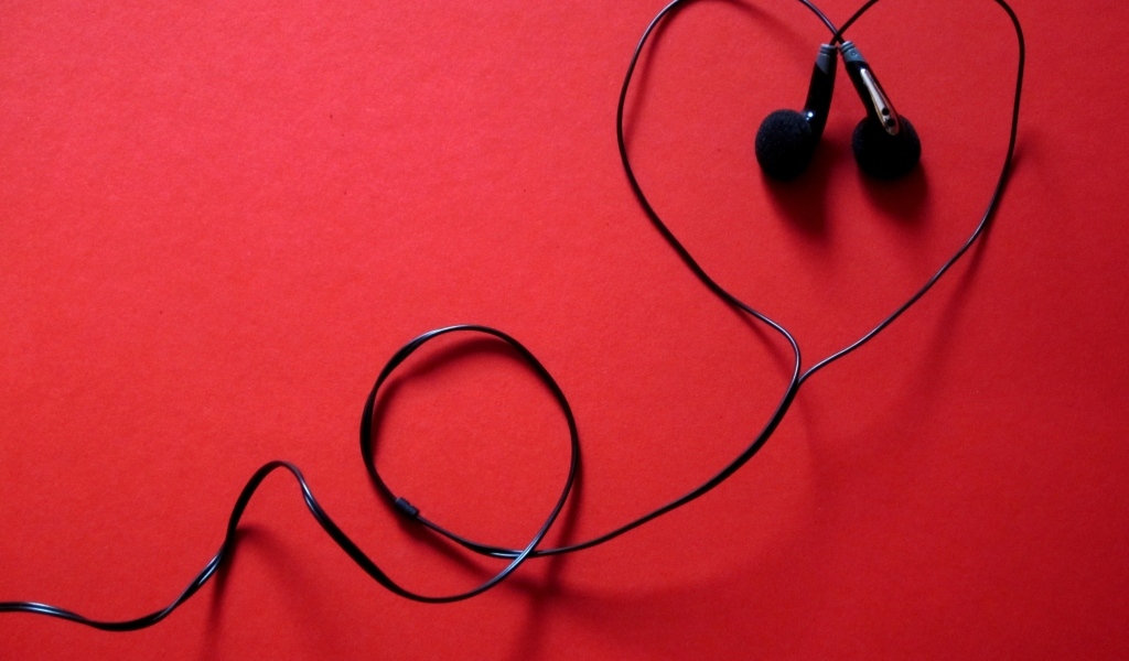 Черные наушники в форме сердца на красном фоне