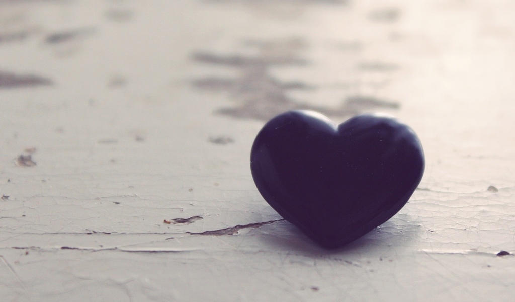 Черное каменное сердце на деревянной поверхности 