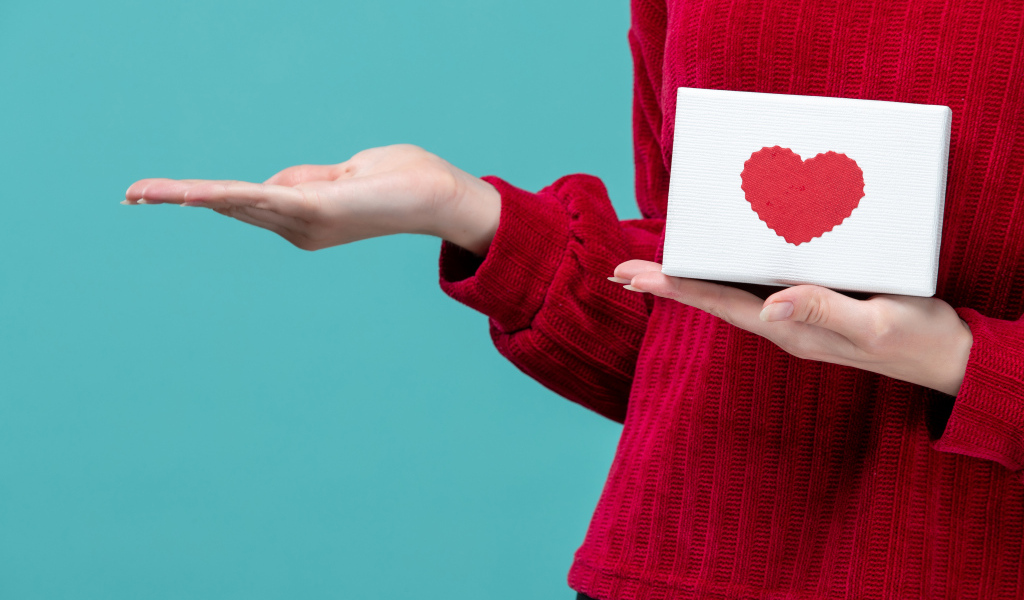 Коробка с сердцем в руке у девушки на голубом фоне