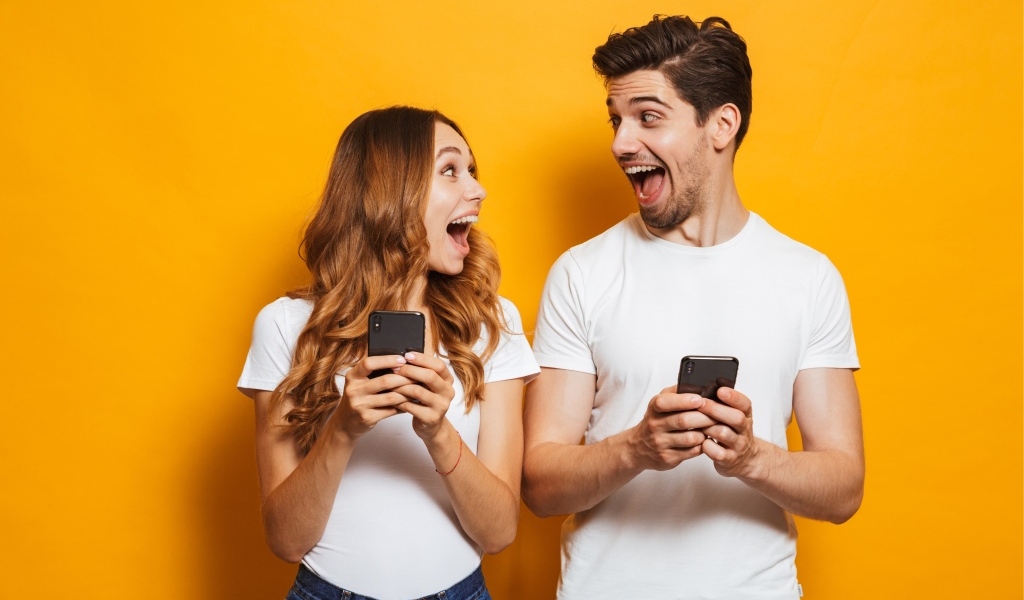 Счастливые парень и девушка с мобильными телефонами