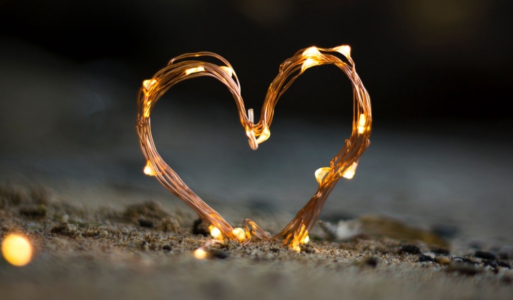 Сердце из гирлянды на песке