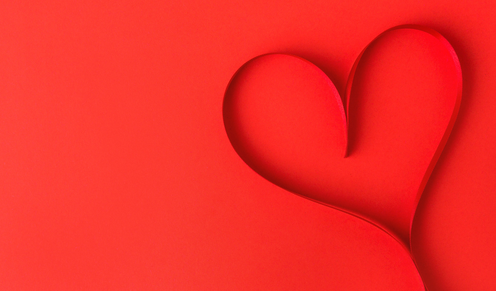 Сердце из атласной ленты на красном фоне