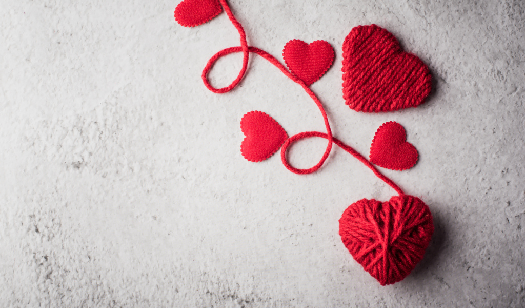 Сердечки из красной шерстяной нити на сером фоне