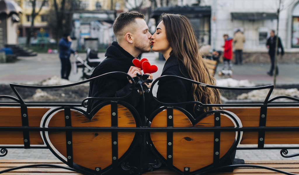 Поцелуй влюбленной пары на лавке в парке