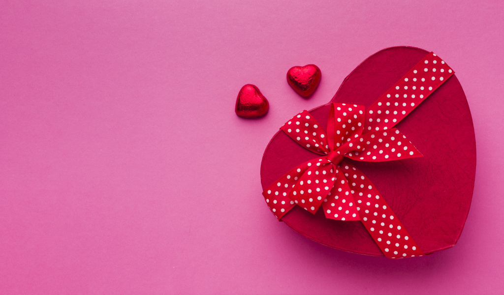 Большая красная коробка в форме сердца на розовом фоне