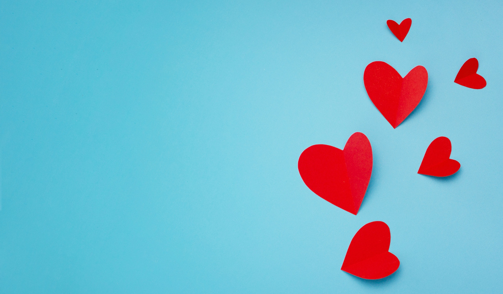 Много красных бумажных сердечек на голубом фоне