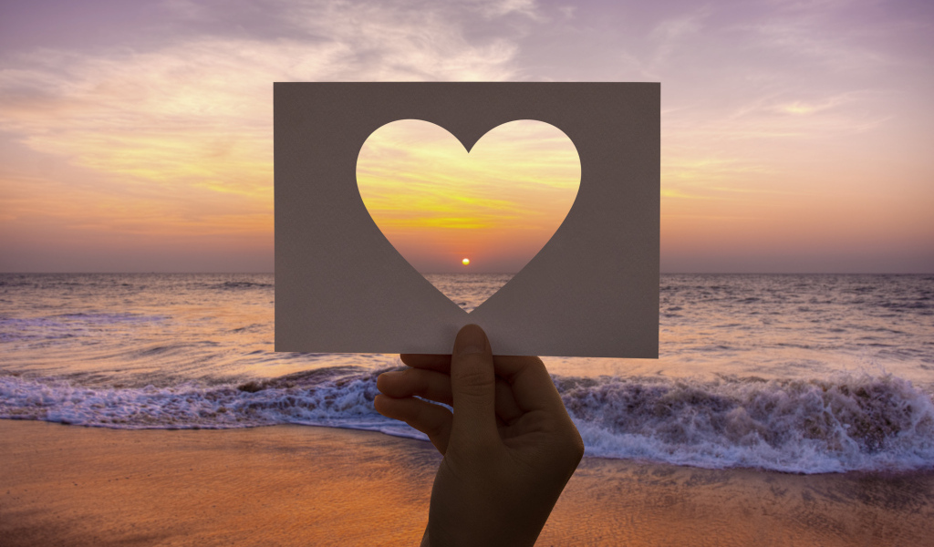 Бумажное сердце на фоне моря на закате солнца