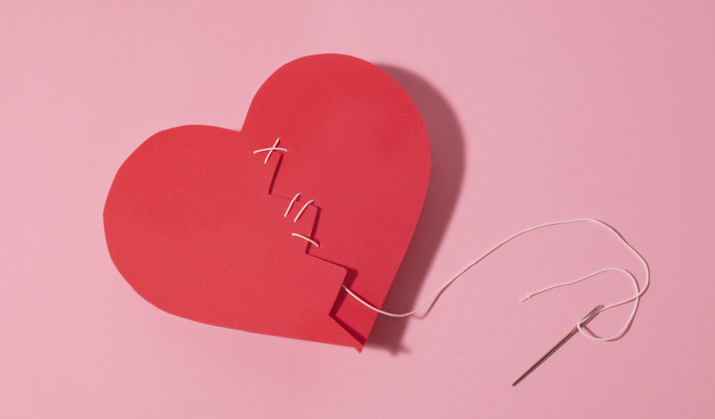 Бумажное сердце сшили нитками на розовом фоне