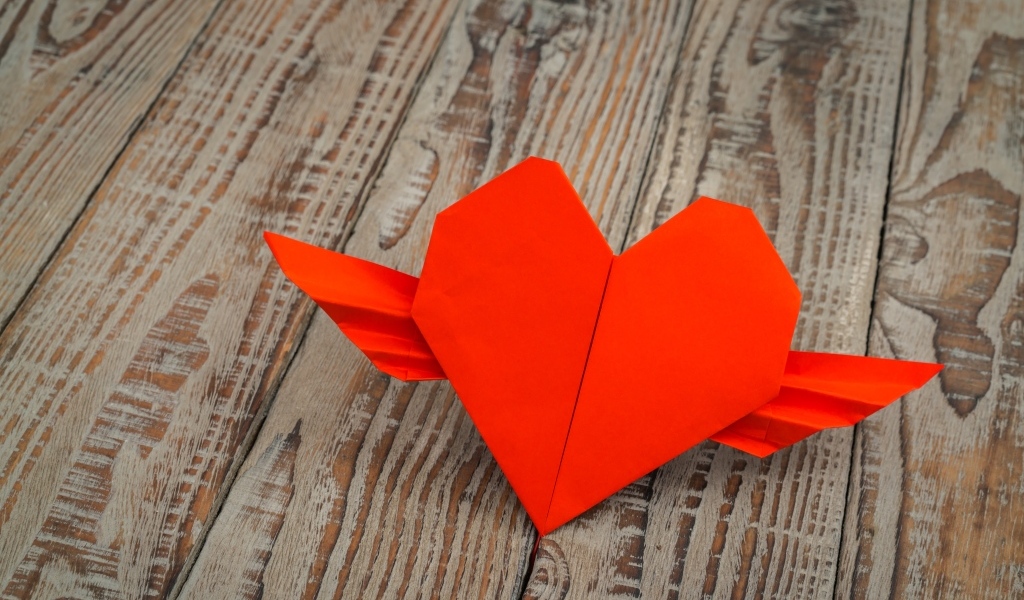 Бумажное красное сердце на деревянных досках