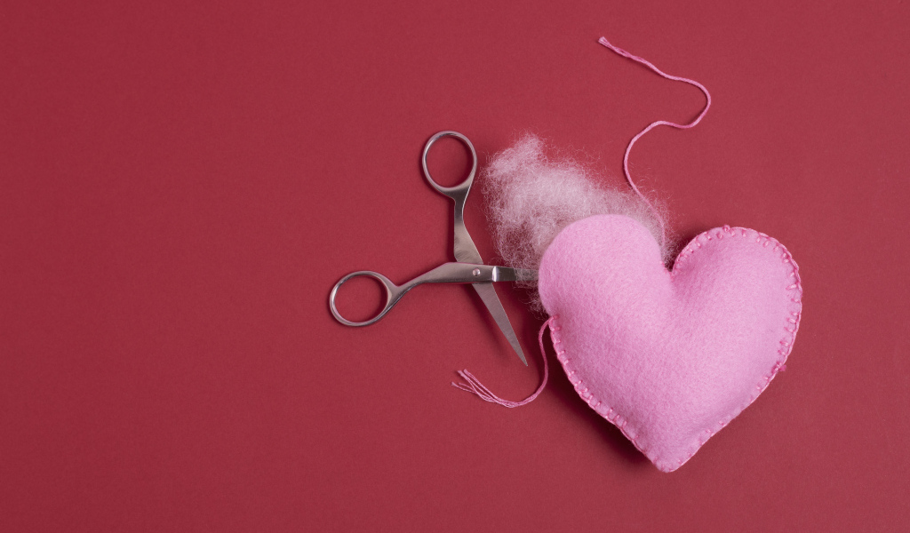 Розовое  сердце с ножницами на красном фоне