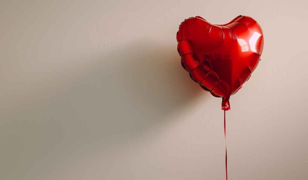 Красный шарик в форме сердца на сером фоне