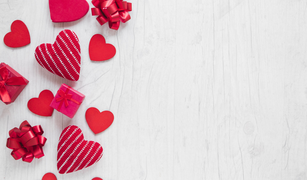 Красные сердечки с подарками и бантами на деревянном фоне