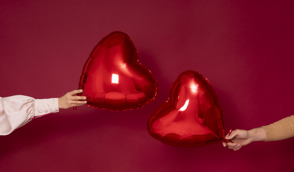 Два воздушных шара в форме сердца на красном фоне