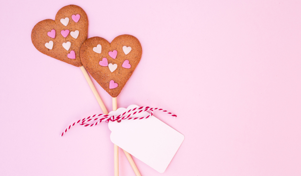 Два сердечка на палочке на розовом фоне