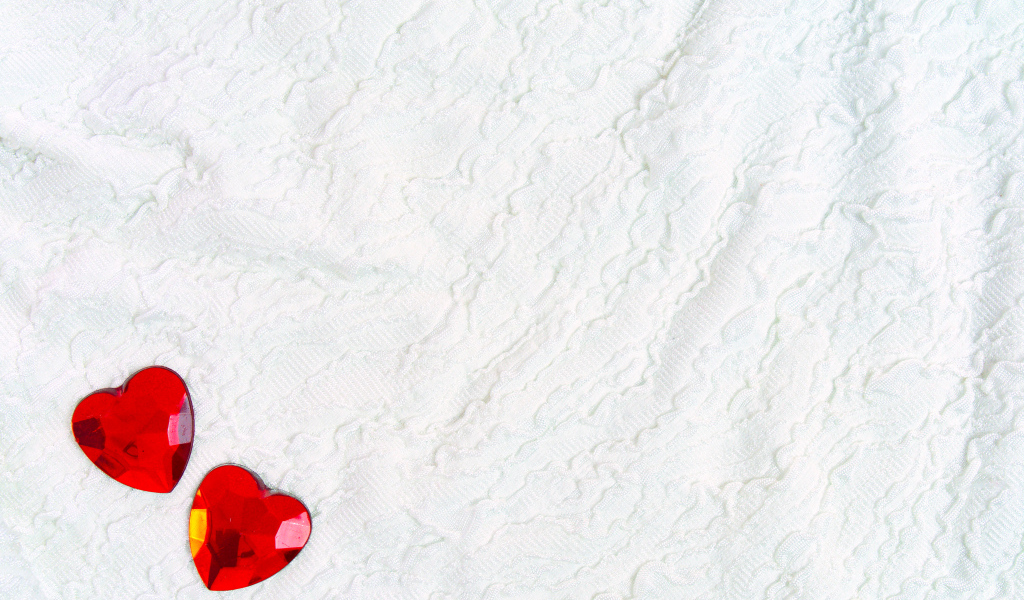Два красных сердца из пластика на белой ткани