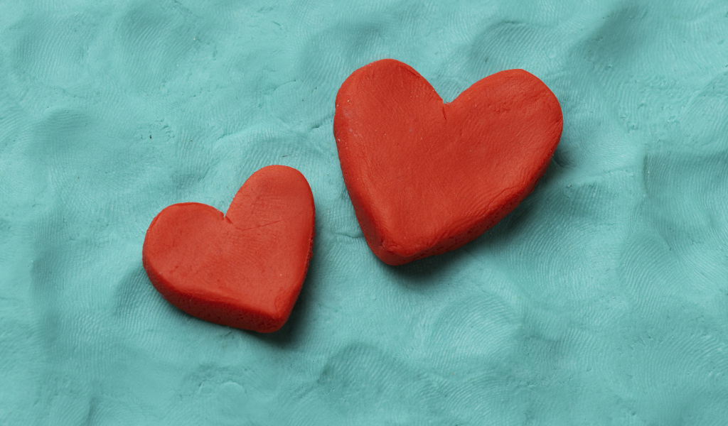 Два красных сердца из пластилина на голубом фоне