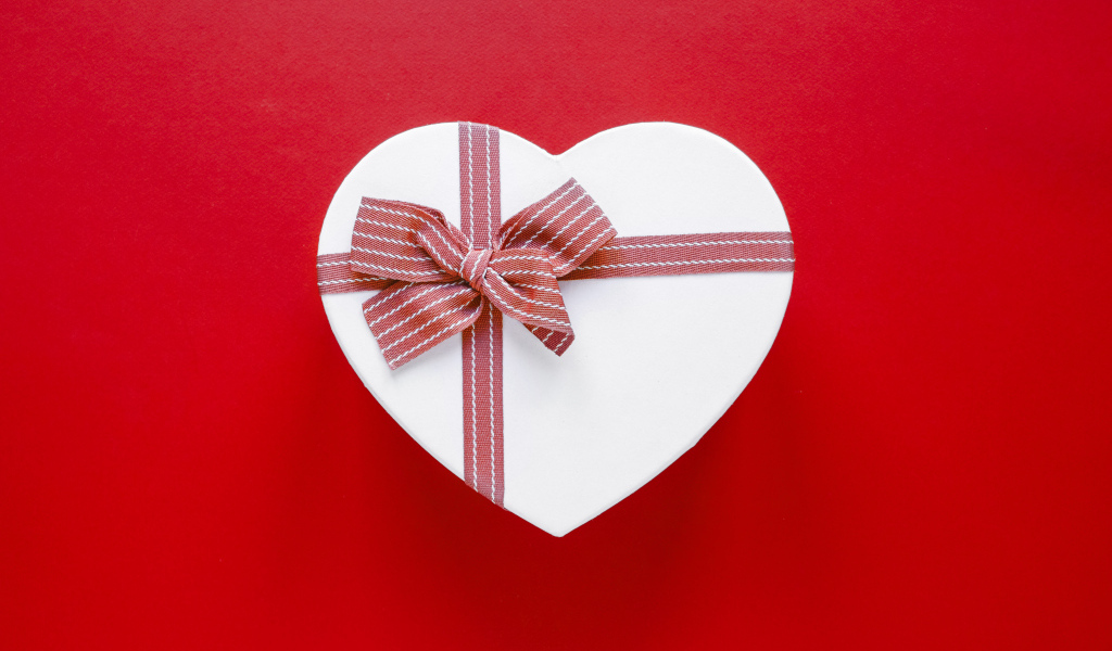 Белая коробка в форме сердца с бантом на красном фоне