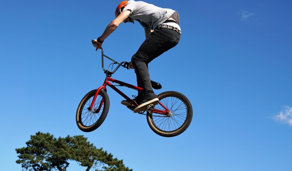 Мужчина делает прыжок на велосипеде на фоне неба